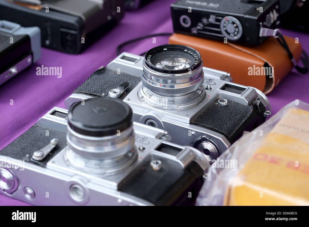 Les appareils photo classiques sont assis sur une nappe violette qui attend les collectionneurs avides. Banque D'Images