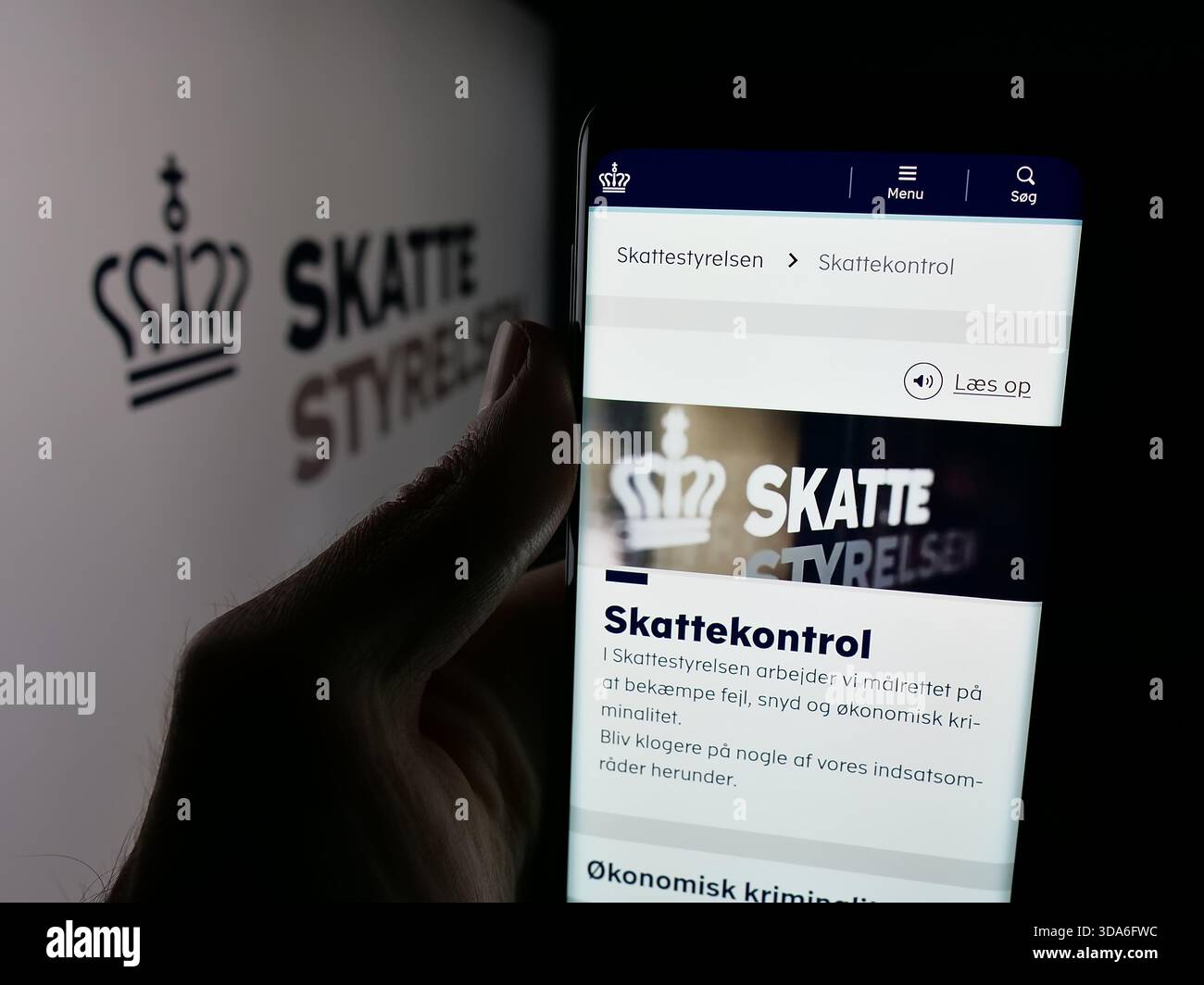 Dans cette illustration photo, une personne tient un téléphone portable avec la page Web de l'agence fiscale danoise Skattestyrelsen sur l'écran devant le logo. Banque D'Images