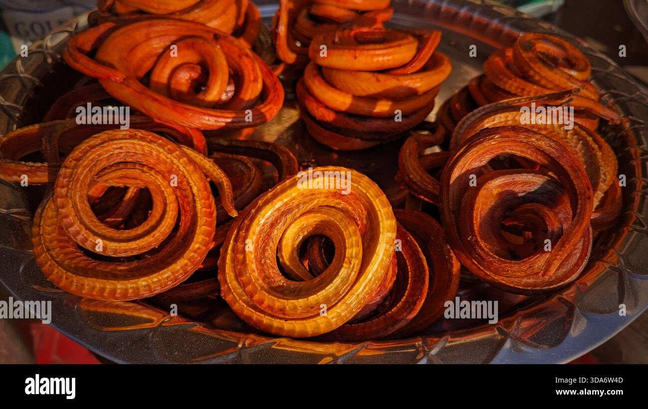 Ceci est une image en gros plan de nombreux aliments enroulés et serpents disposés sur un plateau métallique. Banque D'Images