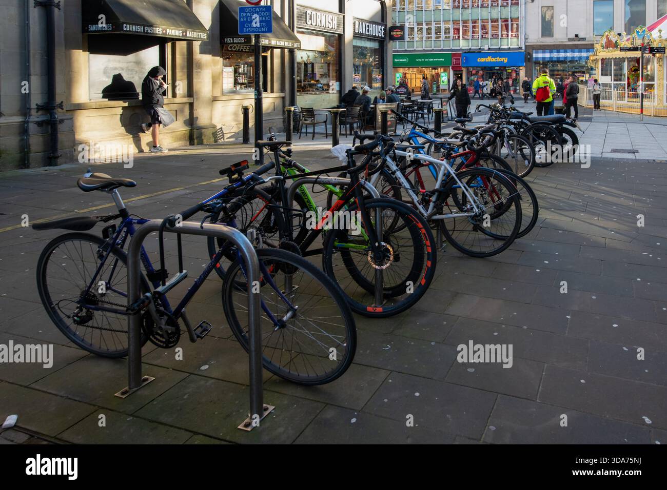 Vélos garés dans des stands de vélos métalliques dans le centre-ville de Cardiff par une journée d'hiver chargée, pays de Galles. Banque D'Images