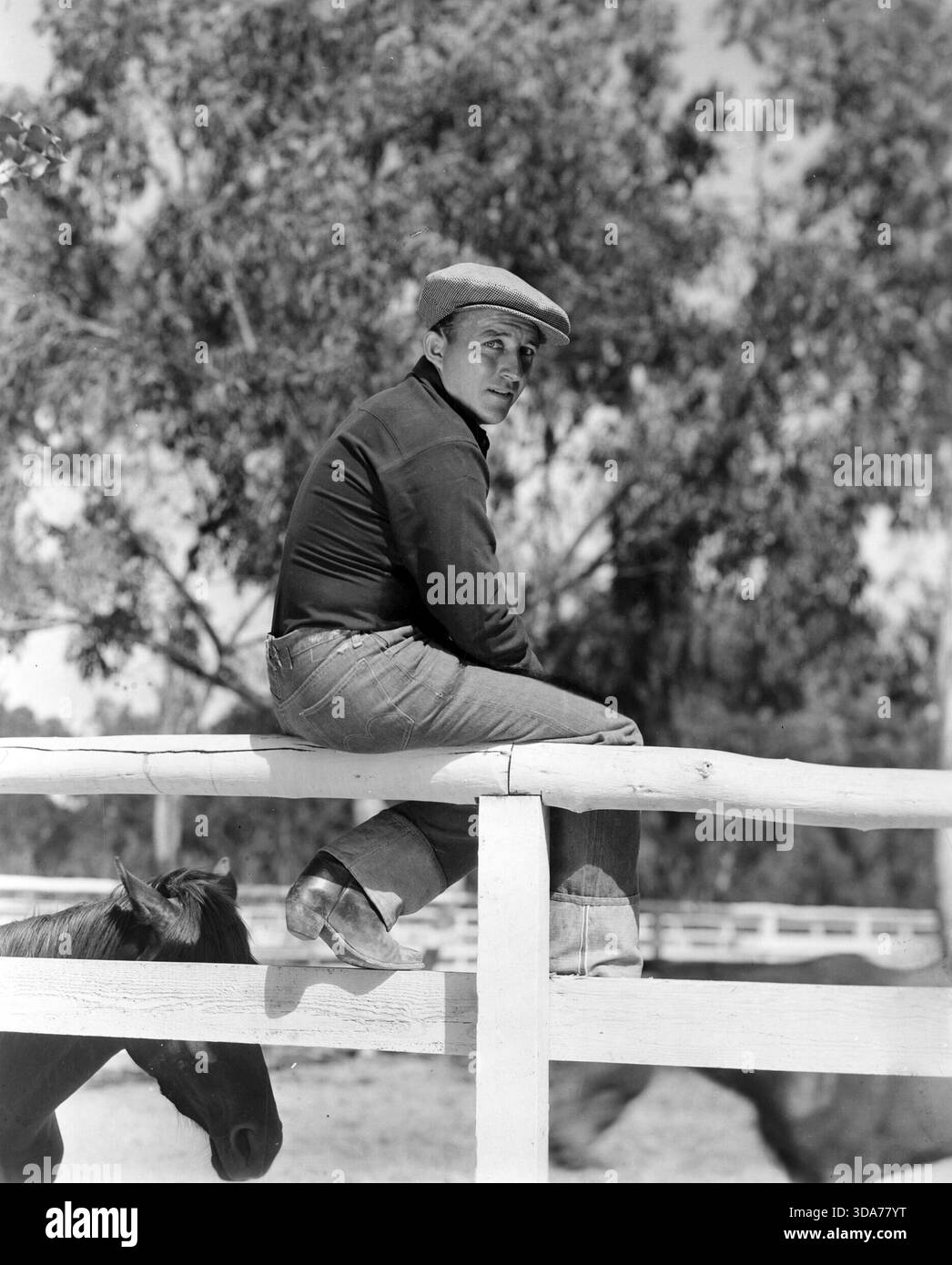 Bing Crosby assis sur une clôture à son ranch (Paramount, 1937). Keybook photo Banque D'Images