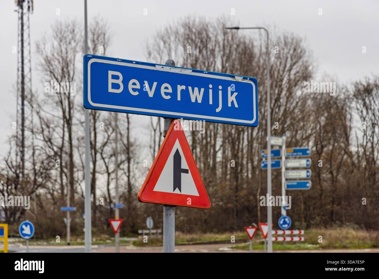 Un panneau routier bleu City Limit marquant l'entrée de la ville néerlandaise de Beverwijk, accompagné d'un panneau de signalisation prioritaire et d'un fond industriel. Banque D'Images