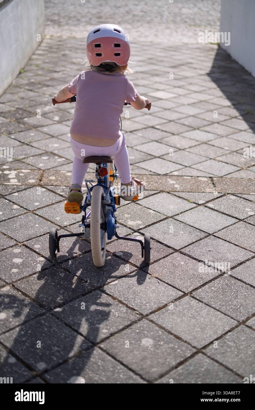 Fille de quatre ans apprenant à monter un vélo Banque D'Images
