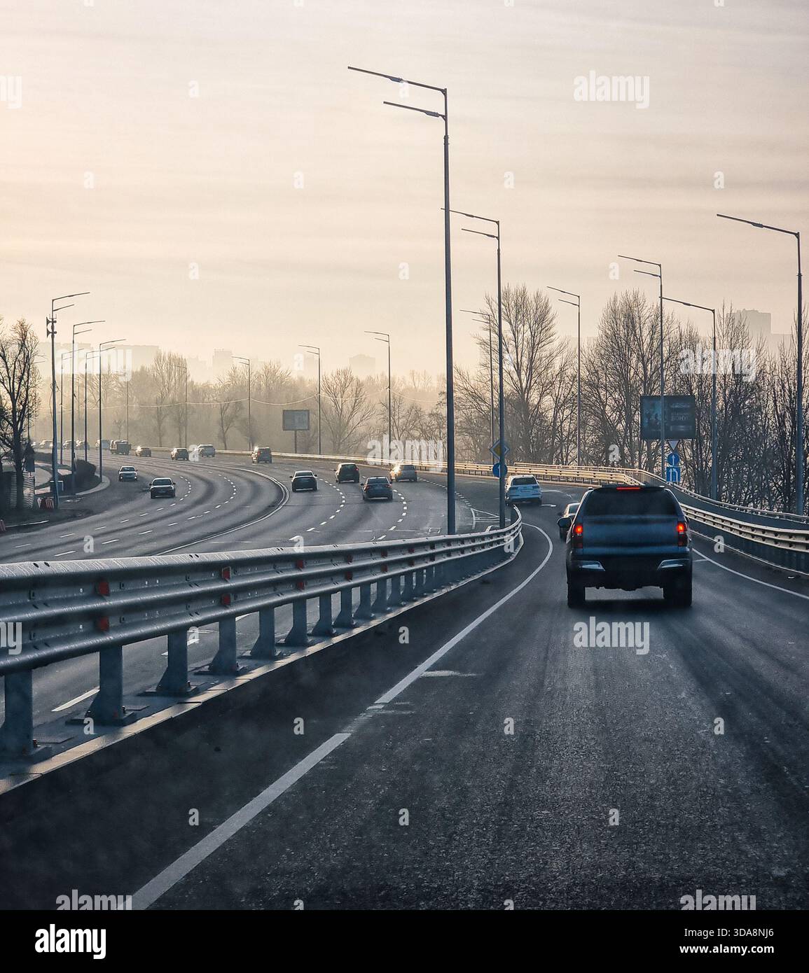 Point de vue : circulation matinale sur une route à plusieurs voies au lever du soleil. En descendant l'autoroute sur la bretelle qui rejoint la route principale avant de tourner vers la gauche. Banque D'Images