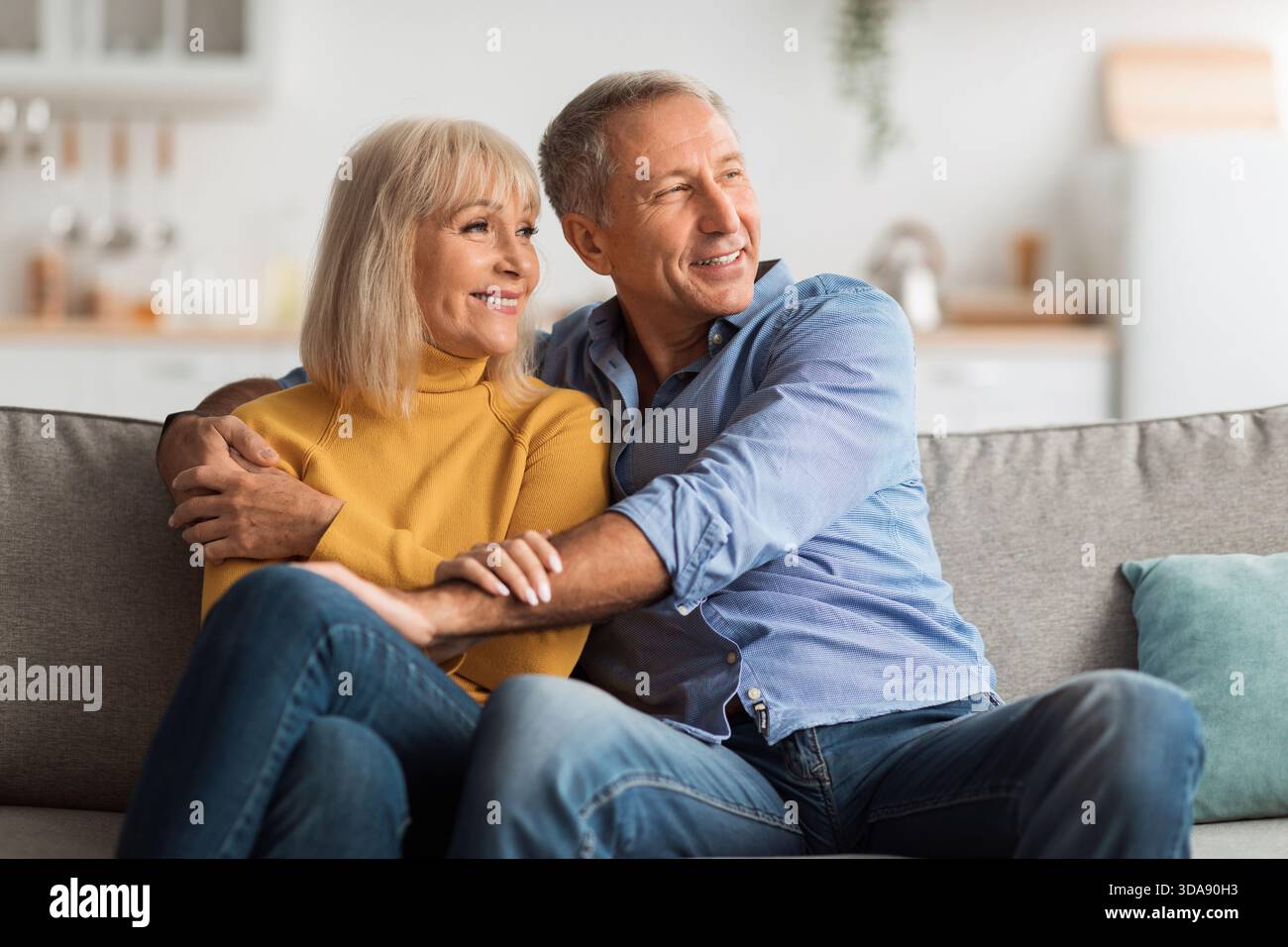 Joyeux couple profite d'un moment confortable ensemble à la maison tout en se relaxant sur le canapé dans un espace de vie lumineux Banque D'Images