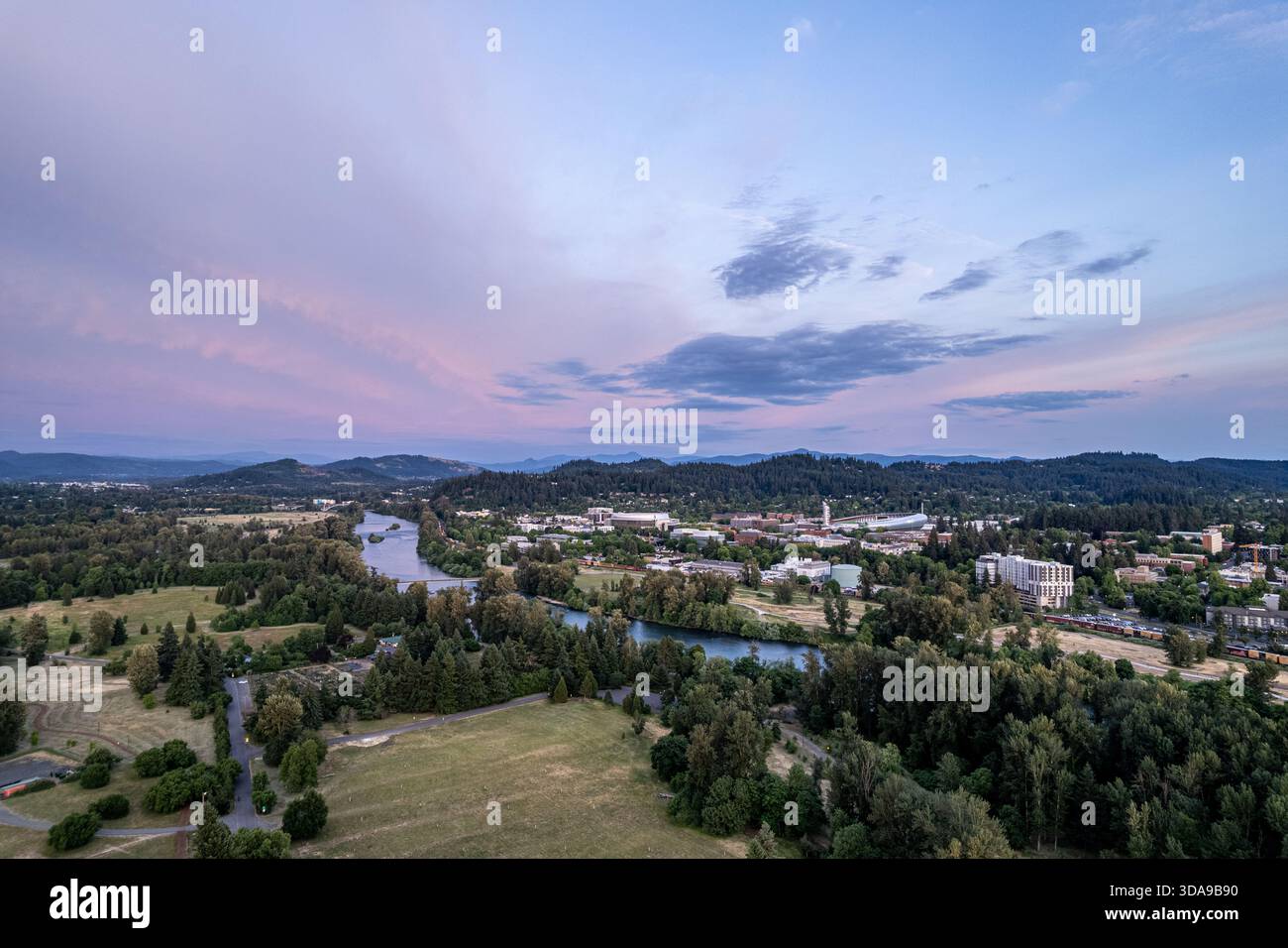 Vue aérienne de la paisible rivière Willamette serpentant à travers une végétation luxuriante, devant le campus de l'Université de l'Oregon sous un ciel pastel, Eugene, Oregon, Banque D'Images