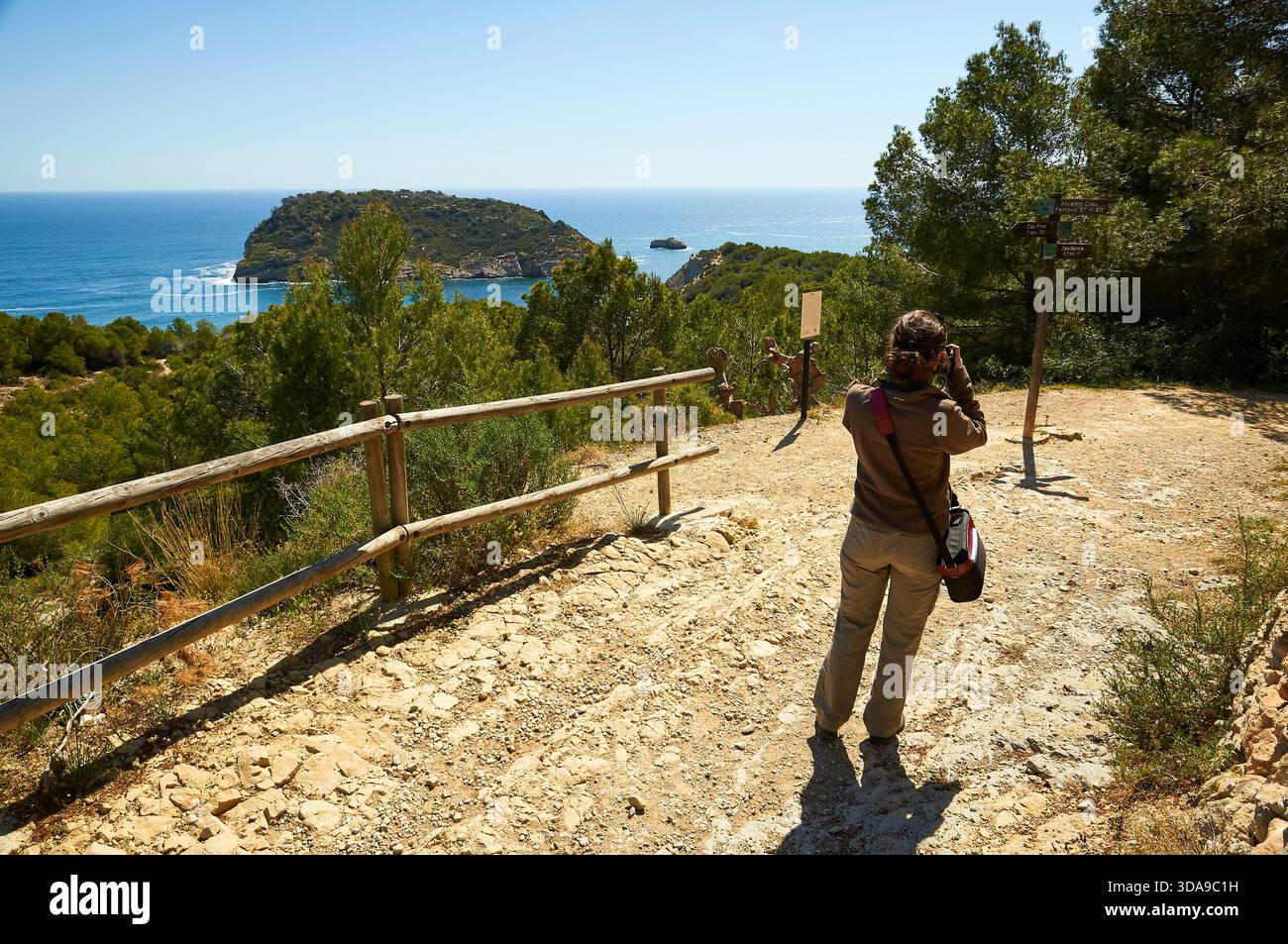 Randonneur photographiant depuis le Mirador Creu del Portitxol dans les randonnées SL-CV 97 et SL-CV 98, avec l'île de Portichol à l'arrière (Jávea, Marina Alta, Alicante) Banque D'Images