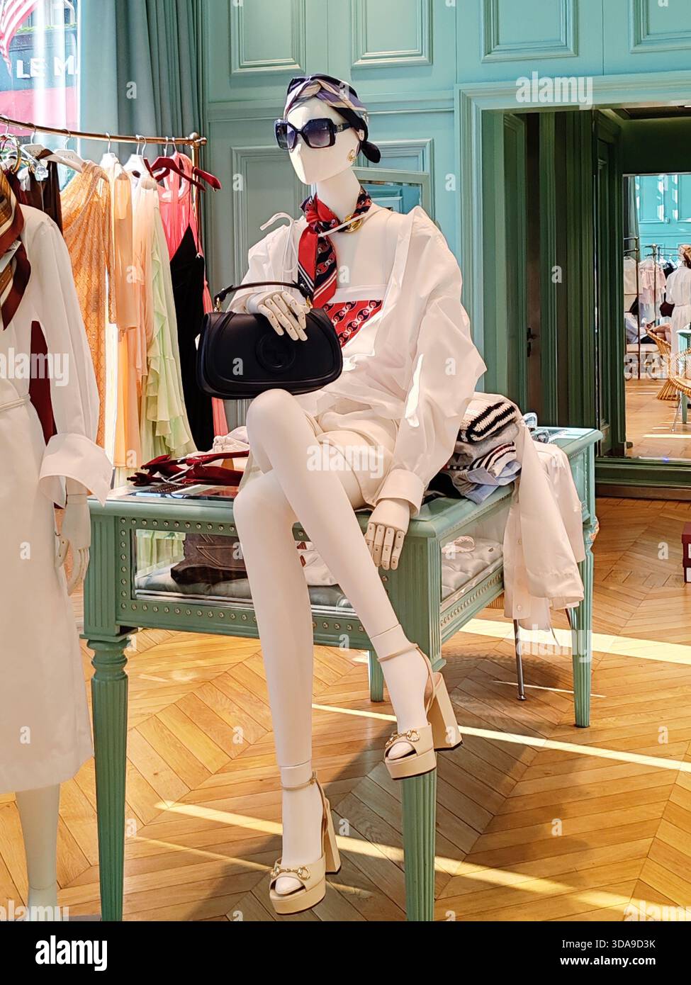 Cannes, France - 7 juin 2025 : mannequin boutique Gucci portant une tenue blanche et tenant un sac à main noir dans un magasin de luxe sur la Croisette Banque D'Images