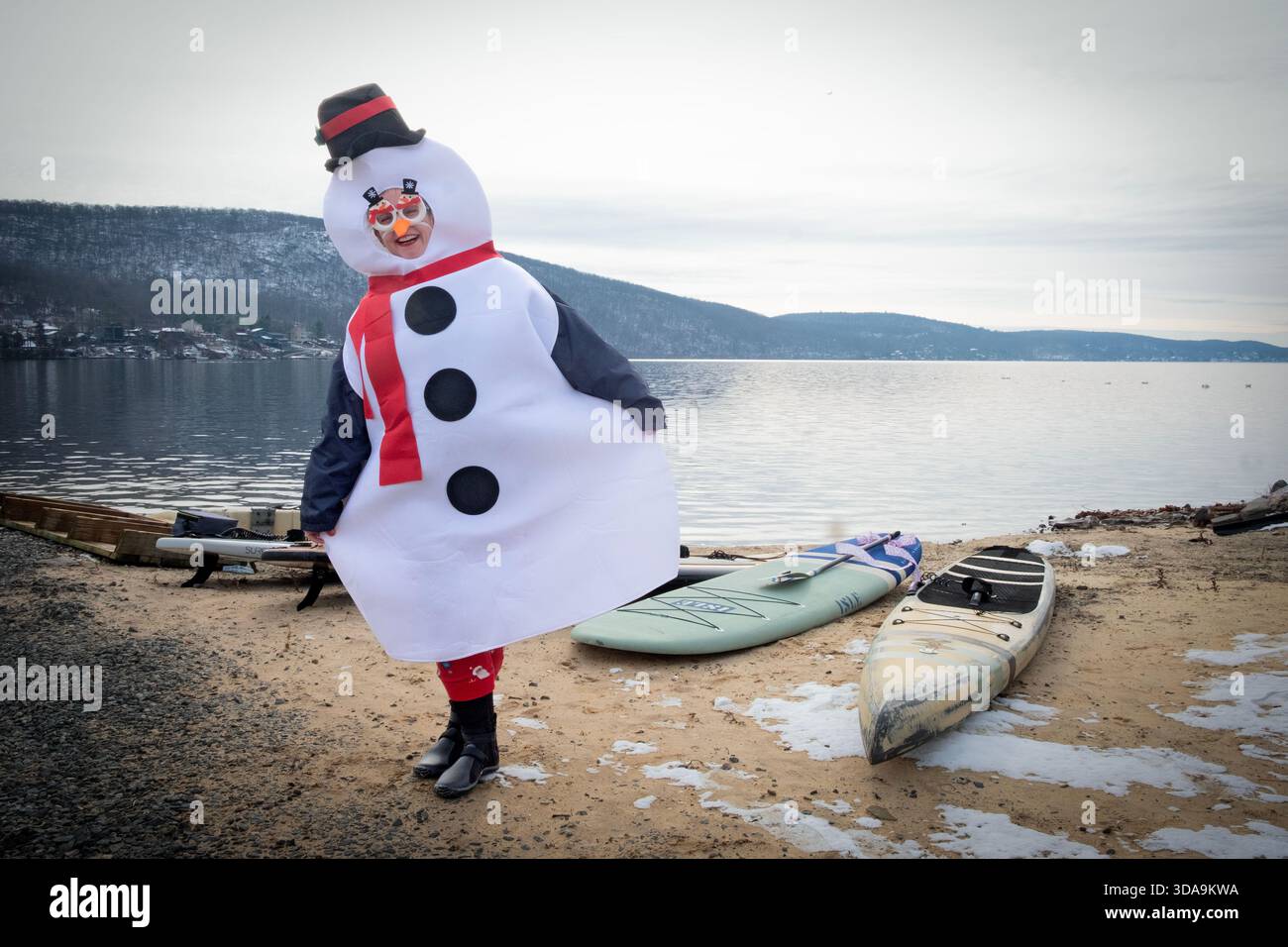 Une dame souriante pose habillée en bonhomme de neige avant l'événement de paddleboard Santa Palooza à Greenwood Lake, comté d'Orange, New York. Banque D'Images