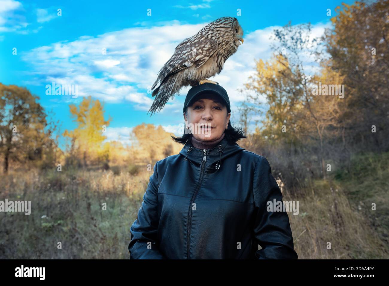 Un beau hibou, le hibou de l'Oural, est assis sur la tête d'une femme. Banque D'Images