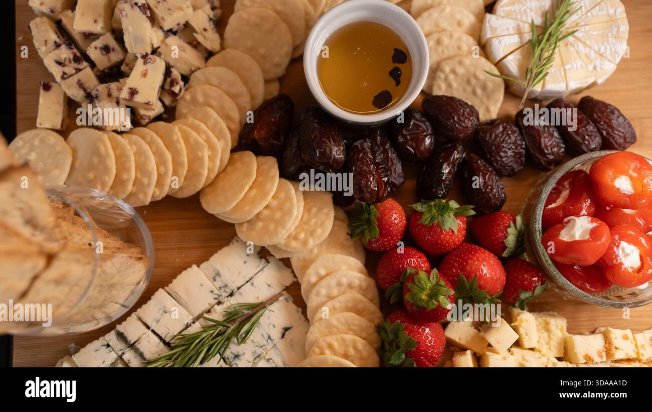 Belle planche de charcuterie avec fromages assortis, fruits frais, dattes et poivrons farcis au fromage à la crème. Parfait pour le partage, les fêtes ou l'application élégante Banque D'Images
