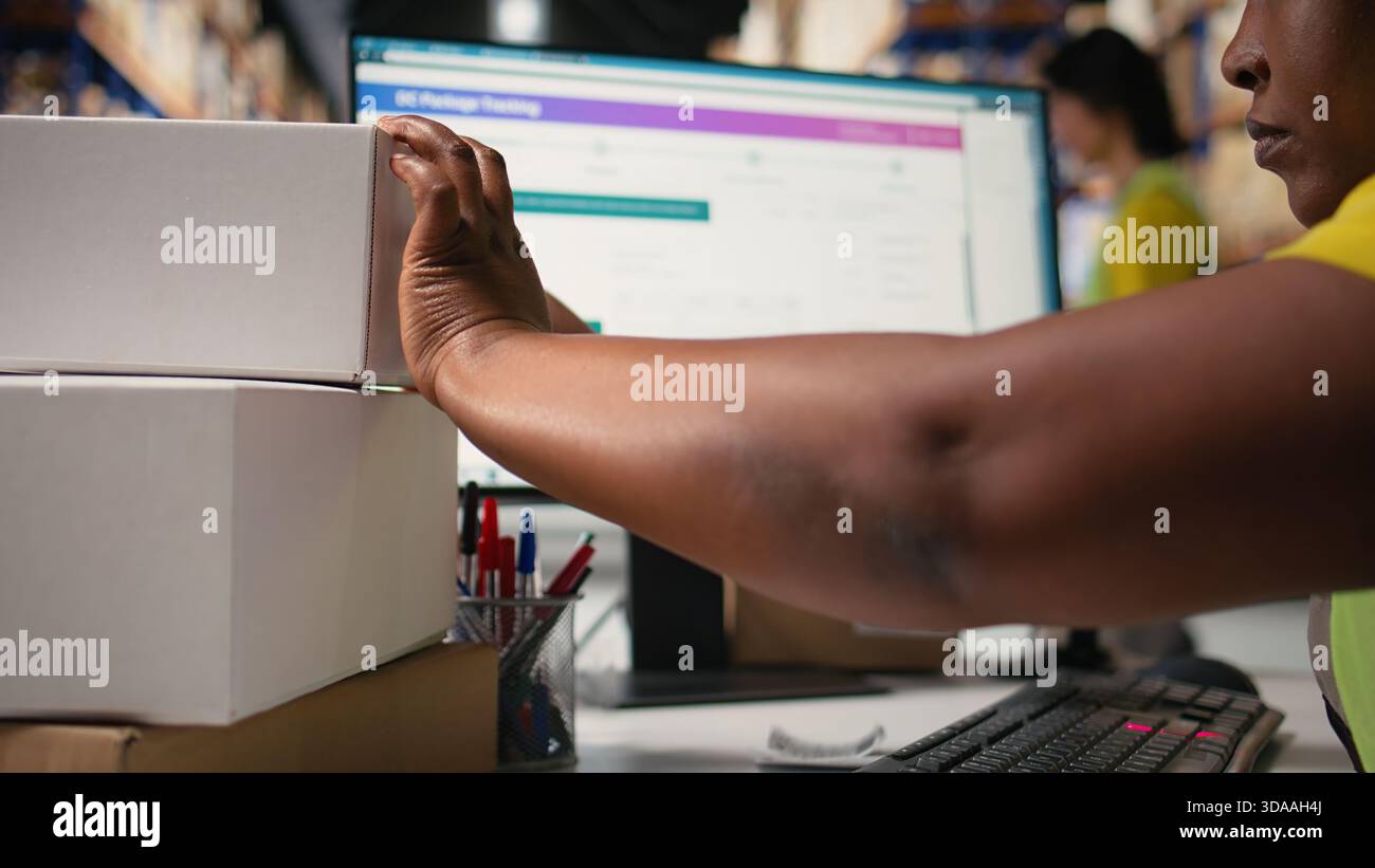 Ouvrière logistique féminine collant des étiquettes d'expédition sur des boîtes en carton, la femme porte un gilet hi vis dans un entrepôt avec des informations de suivi de code à barres sur les étiquettes. Traitement des commandes et suivi des colis. Caméra A. Banque D'Images