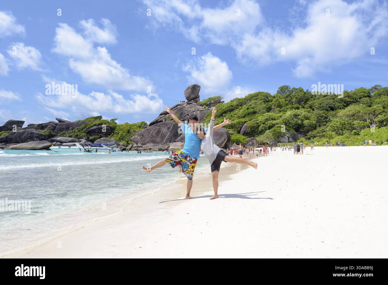 Couple de touristes leva les bras et les jambes avec Happy sur la plage près de la mer sous le ciel bleu et nuage de l'été à Koh Similan Island à Mu Ko Similan Nat Banque D'Images