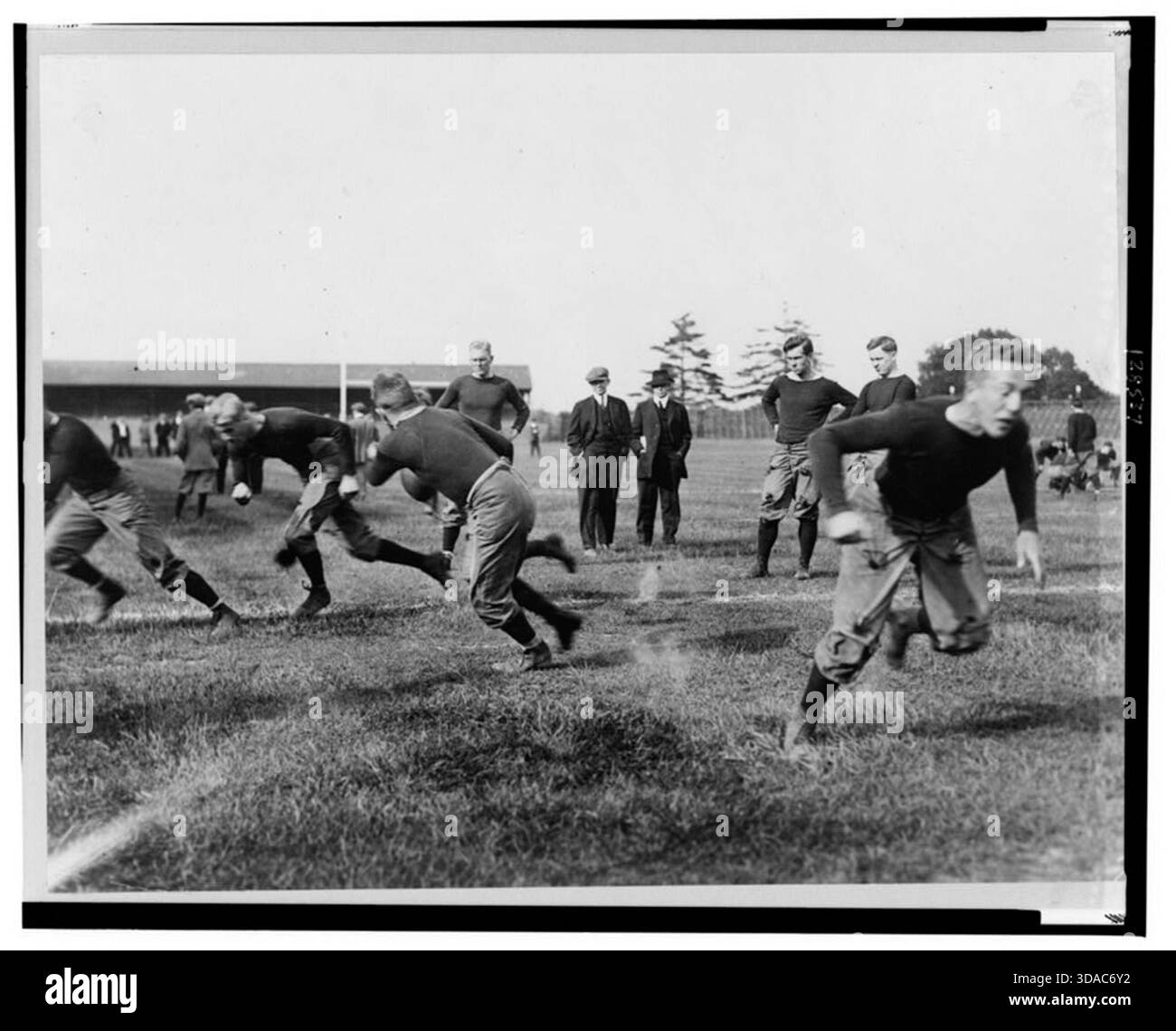 Photo historique vintage de joueurs de football de Yale pratiquant sur le terrain, avec des athlètes exécutant des exercices et des entraîneurs observant en arrière-plan, vers 1908–1915. Banque D'Images
