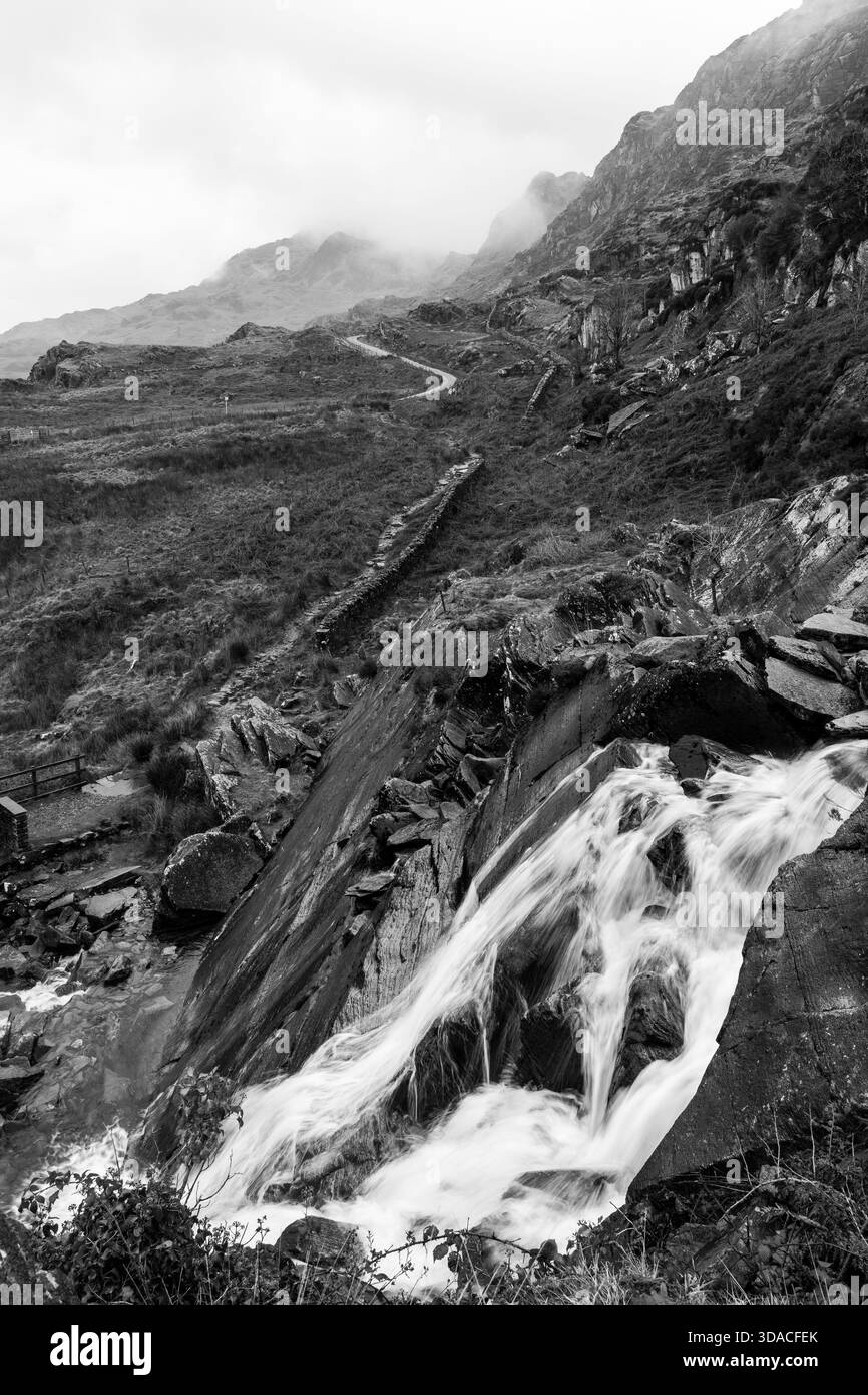 Cascade de Cwmorthin coulant sur des dalles de roche avec un fond sombre en noir et blanc Banque D'Images