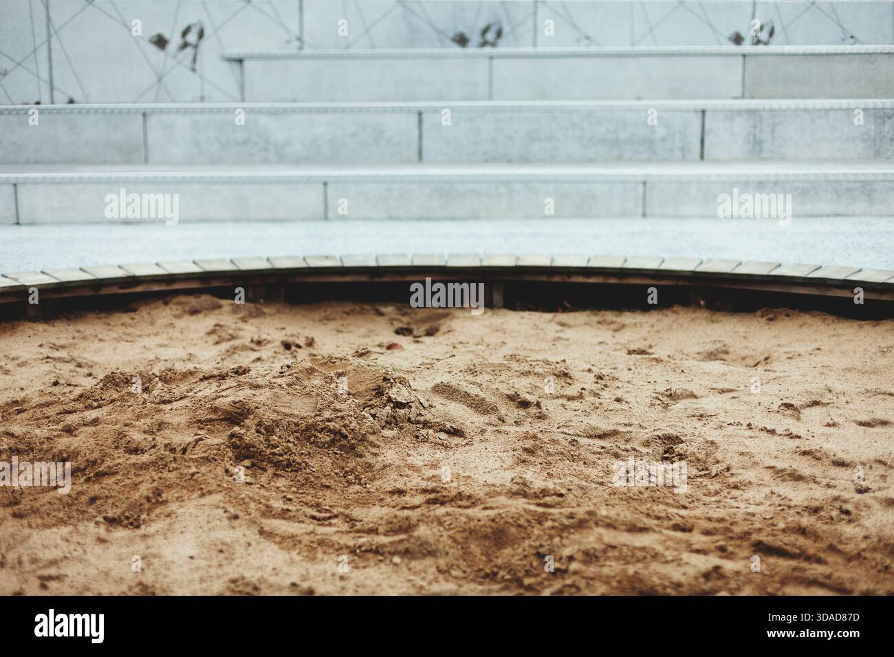 Bac à sable vide rond devant les marches en béton gris dans une aire de jeux sans enfants Banque D'Images