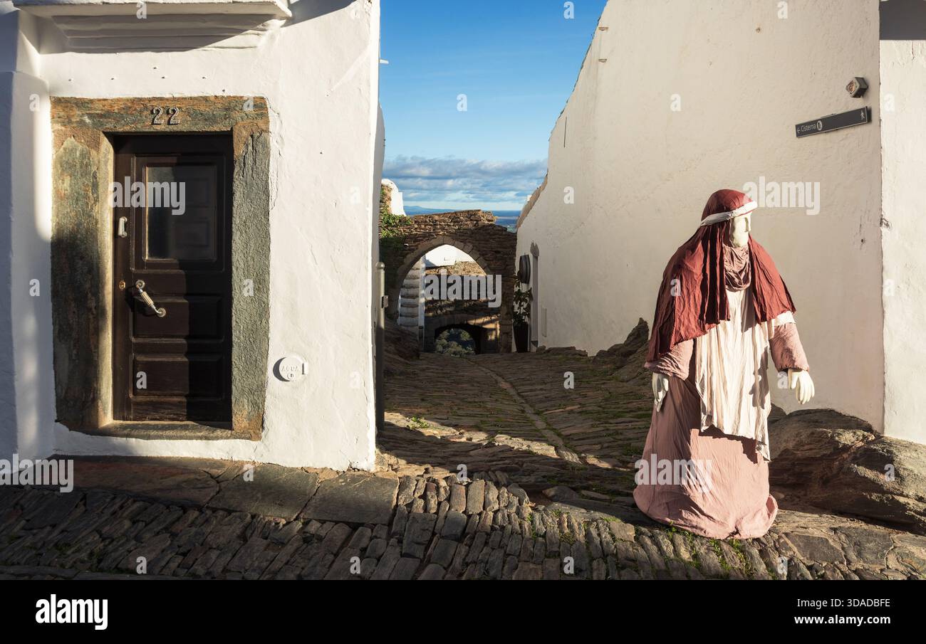 Monsaraz, Portugal - 07 décembre 2024 : une rue latérale et une ruelle à Monsaraz, Portugal, avec un personnage d'une scène de nativité en plein air. Banque D'Images