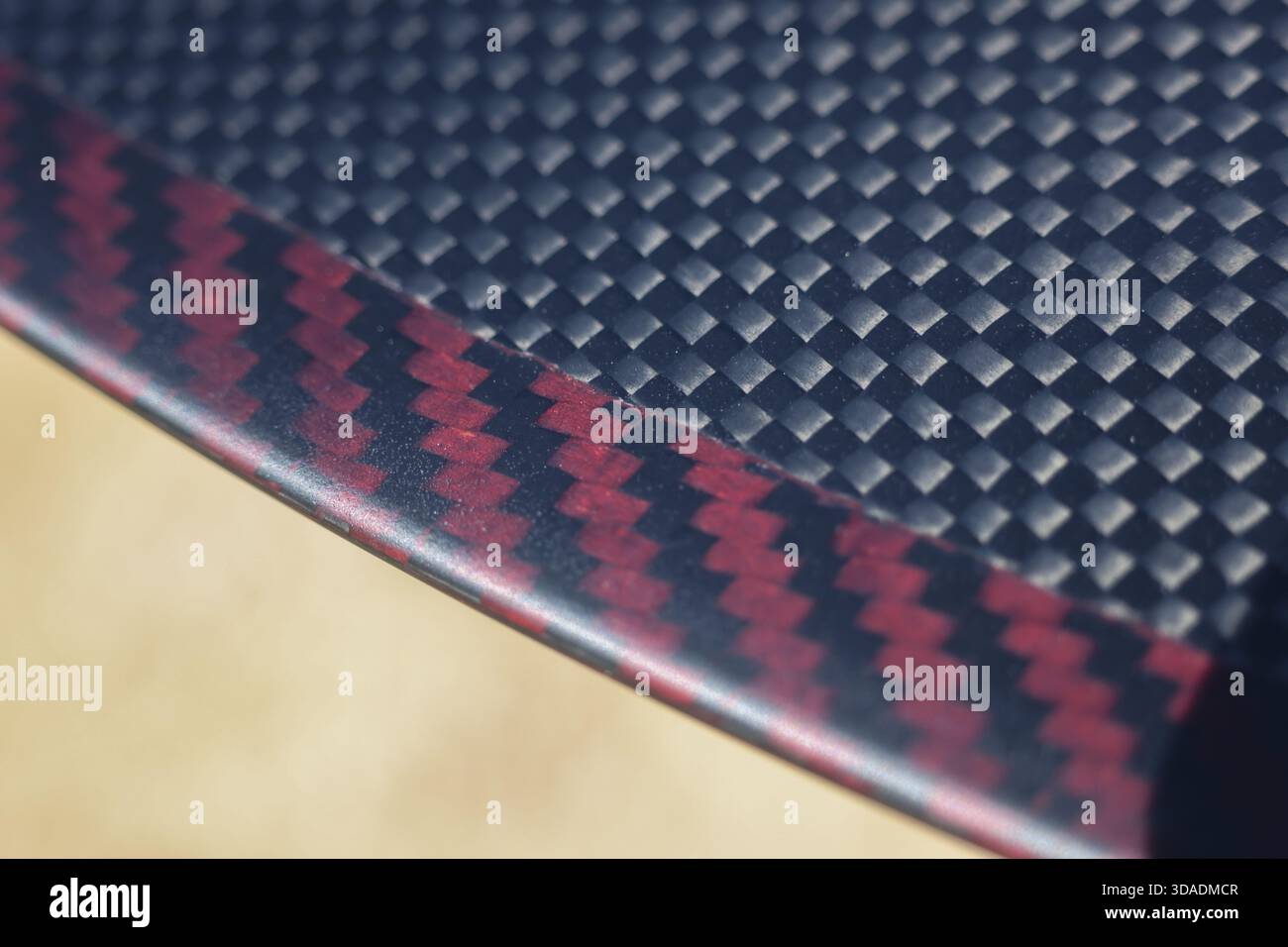 Matériau composite en fibre de carbone noir et rouge élégant. Ce fond abstrait moderne présente une texture tissée détaillée et un motif géométrique idéal pour Banque D'Images
