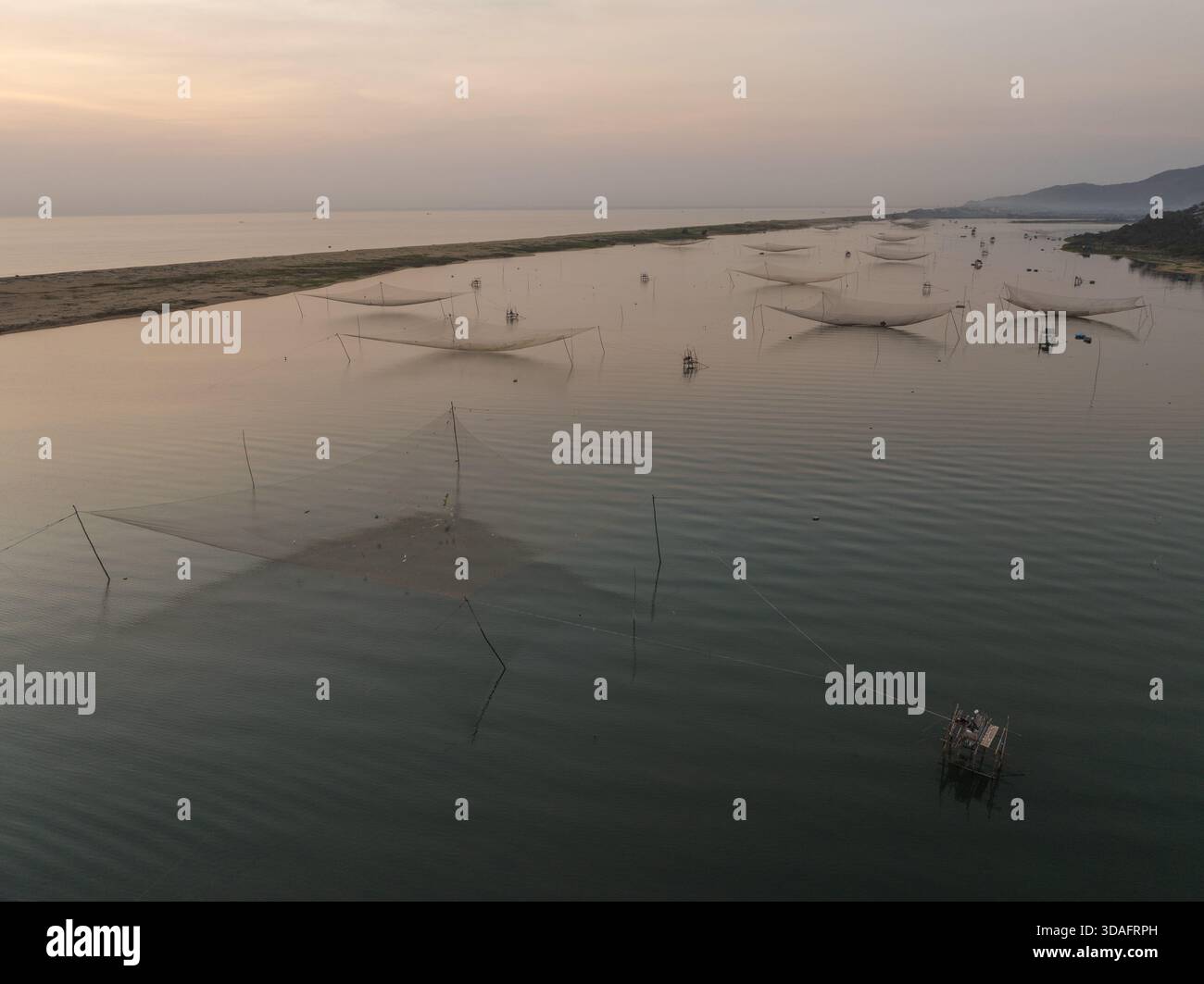 Vue aérienne de filets de pêche symétriques reflétant les eaux tranquilles sous un ciel doux, à l'aube, Hoai Nhon, Binh Dinh, Vietnam. Banque D'Images