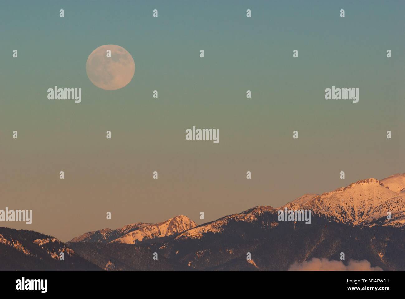 Vue aérienne d'une pleine lune suspendue au-dessus des sommets enneigés des montagnes Low Tatras, touchée par la lueur chaude du soleil couchant, Low Ta Banque D'Images