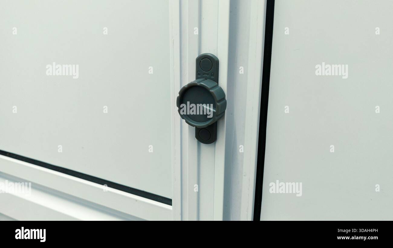 Gros plan du cadran en plastique gris moderne ou du mécanisme de verrouillage sur la porte de salle de bains en PVC blanc ou le cadre de fenêtre Banque D'Images