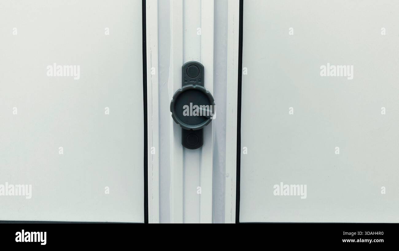 Gros plan du cadran en plastique gris moderne ou du mécanisme de verrouillage sur la porte de salle de bains en PVC blanc ou le cadre de fenêtre Banque D'Images