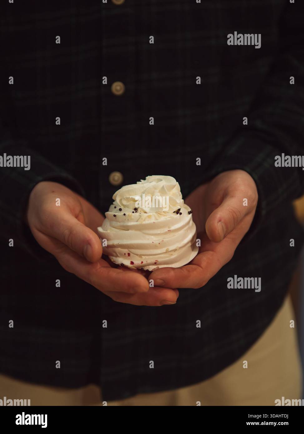 Homme tenant un gâteau meringue en basse lumière chaude – gros plan vertical Banque D'Images