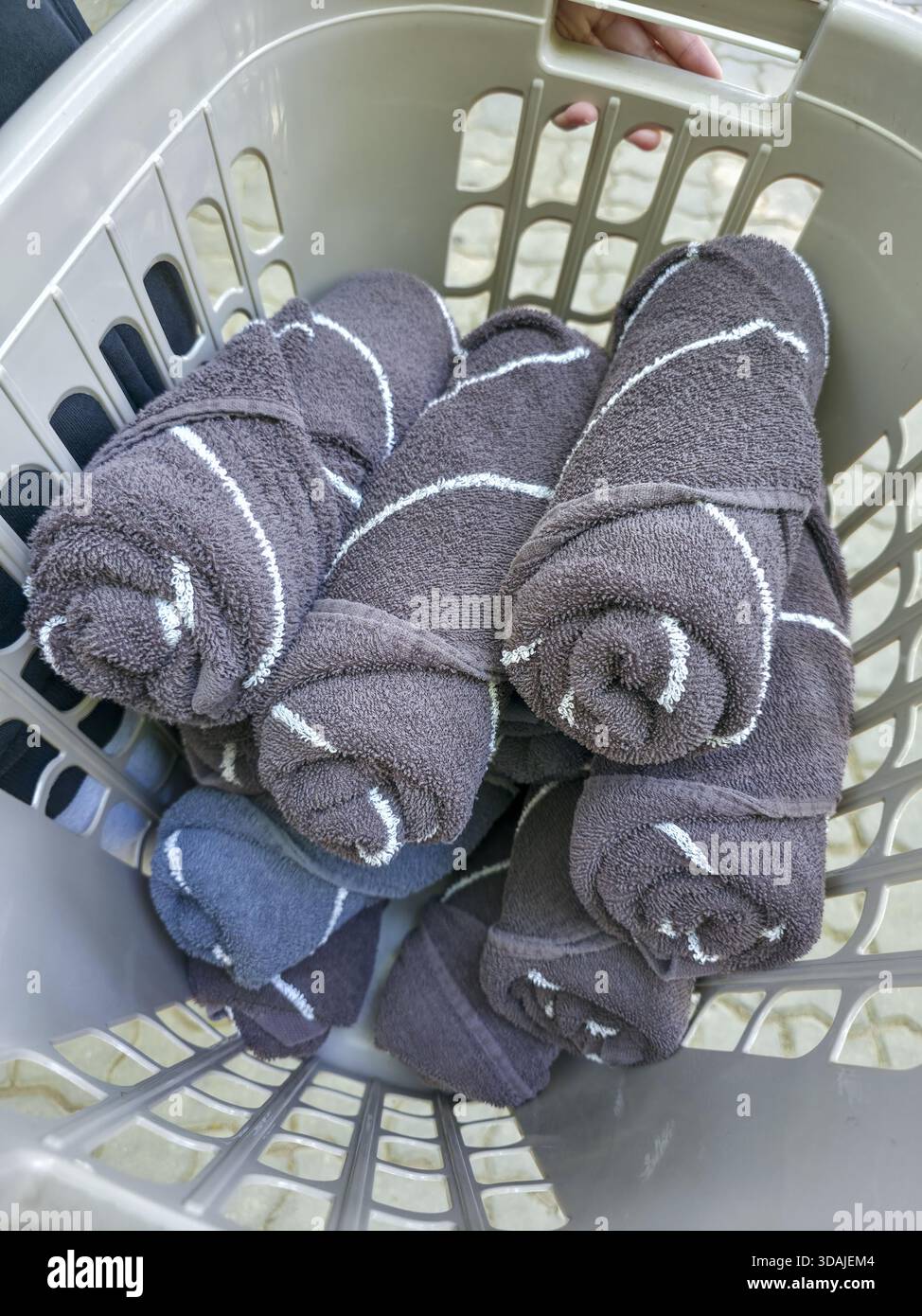 Pile satisfaisante de serviettes roulées grises propres avec motif rayé dans le panier à linge. résultat soigneusement organisé des travaux ménagers et de la corvée finie, frais et Banque D'Images