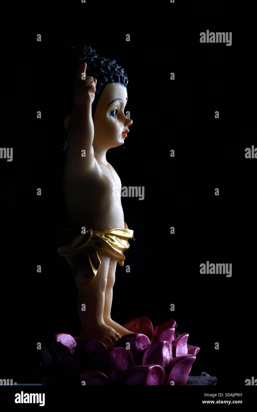 Figure de Bouddha asiatique assise gracieusement, offrant bénédiction et paix, capturée sous un éclairage dramatique, fond minimaliste. Banque D'Images