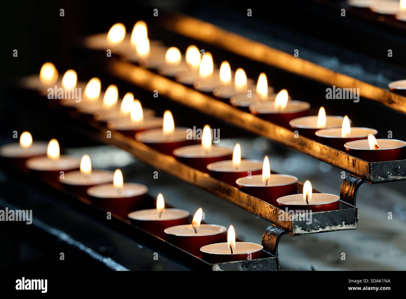 Basilique San Clemente. Des rangées de bougies chauffe-plat votives scintillent dans une église, une douce lueur illuminant le silence de prière. Banque D'Images