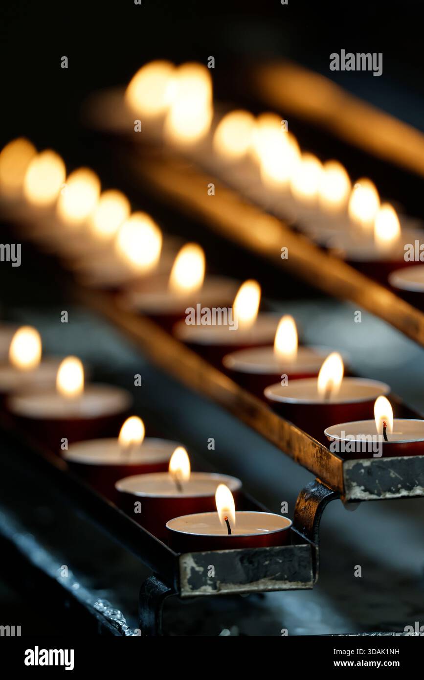 Basilique San Clemente. Des rangées de bougies chauffe-plat votives scintillent dans une église, une douce lueur illuminant le silence de prière. Banque D'Images