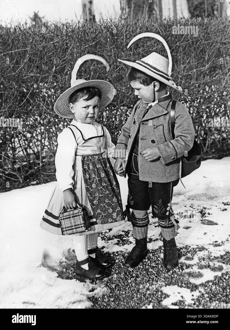 Garçon et fille en costume bavarois traditionnel se tiennent la main dans le jardin avant. [traduction automatique] Banque D'Images