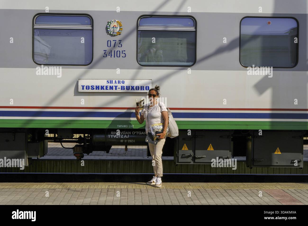 Touriste souriant debout devant un train à Boukhara, Ouzbékistan Banque D'Images