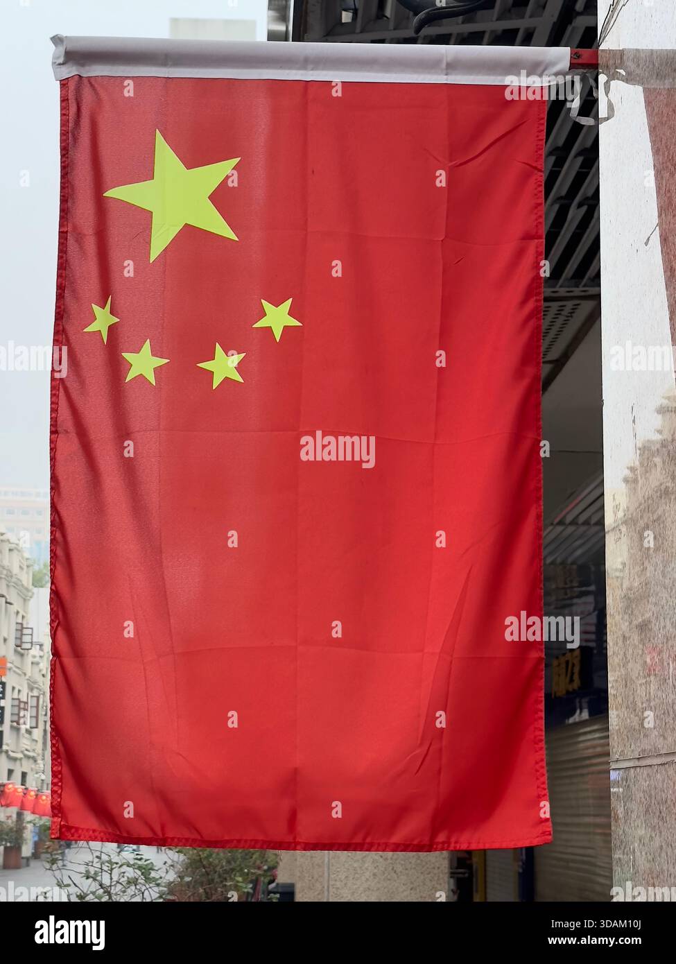 Drapeau chinois suspendu verticalement à l'extérieur d'un bâtiment dans un cadre urbain Banque D'Images