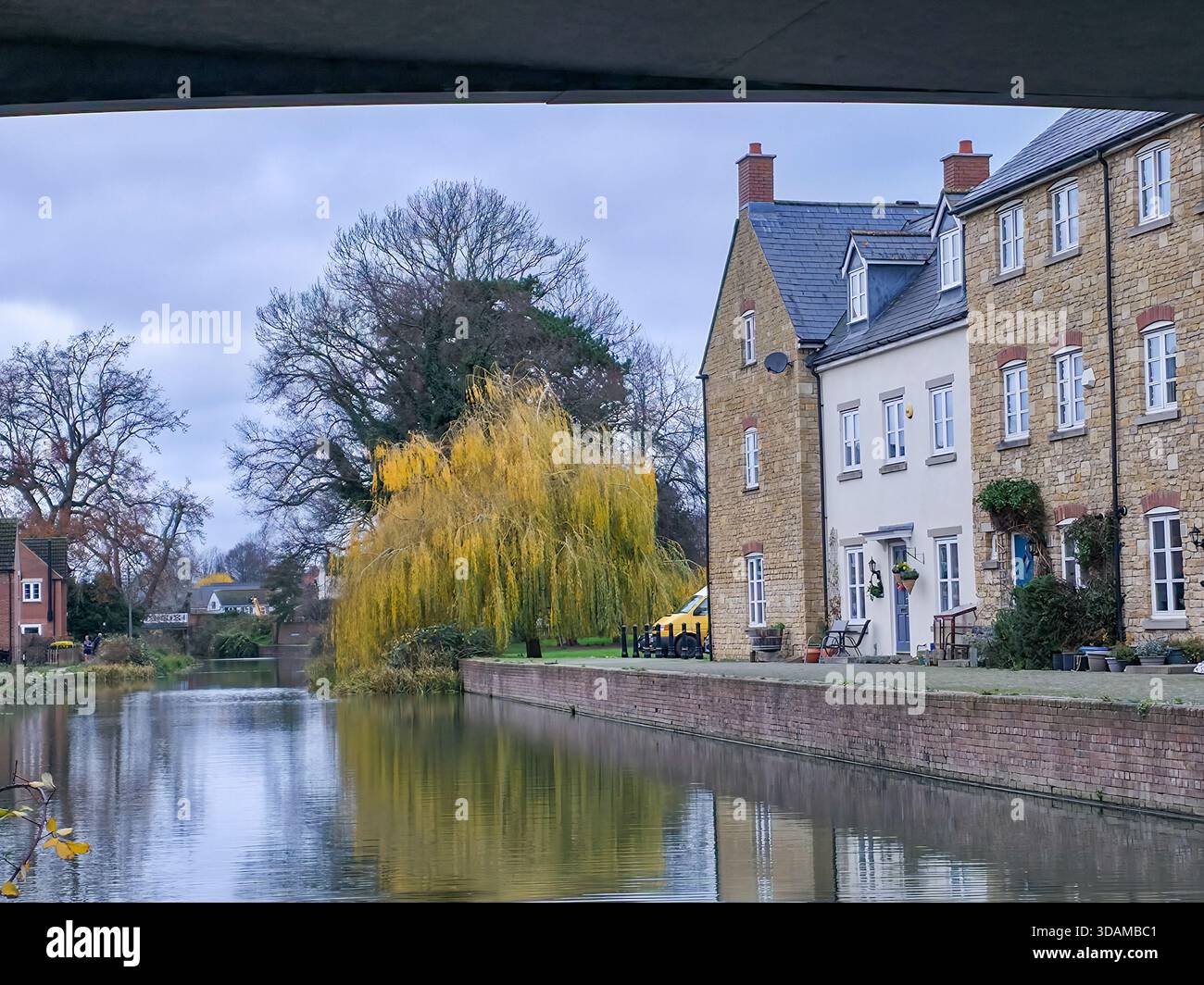 Rangée de maisons traditionnelles au bord du canal avec reflet d'arbres de saule sur le calme canal Stroudwater en hiver, Stroud, Cotswolds, Gloucestershire, Angleterre, - Image de stock capturée avec un smartphone