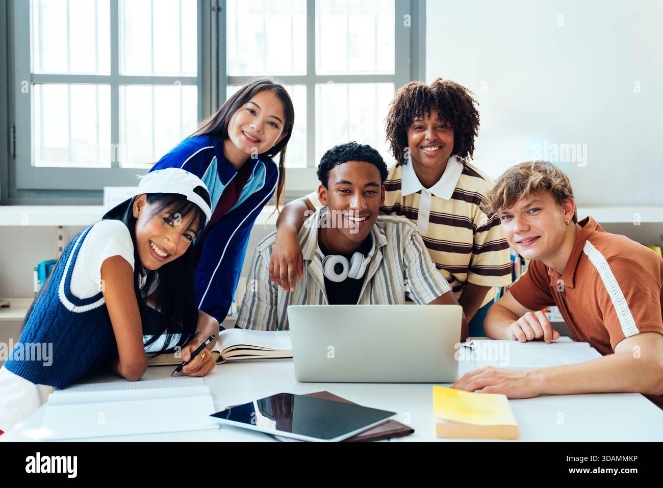 Groupe multiethnique de jeunes étudiants se réunissant à la bibliothèque - divers adolescents collaborant sur le projet à la bibliothèque, assis autour de la table avec l'ordinateur portable A. Banque D'Images