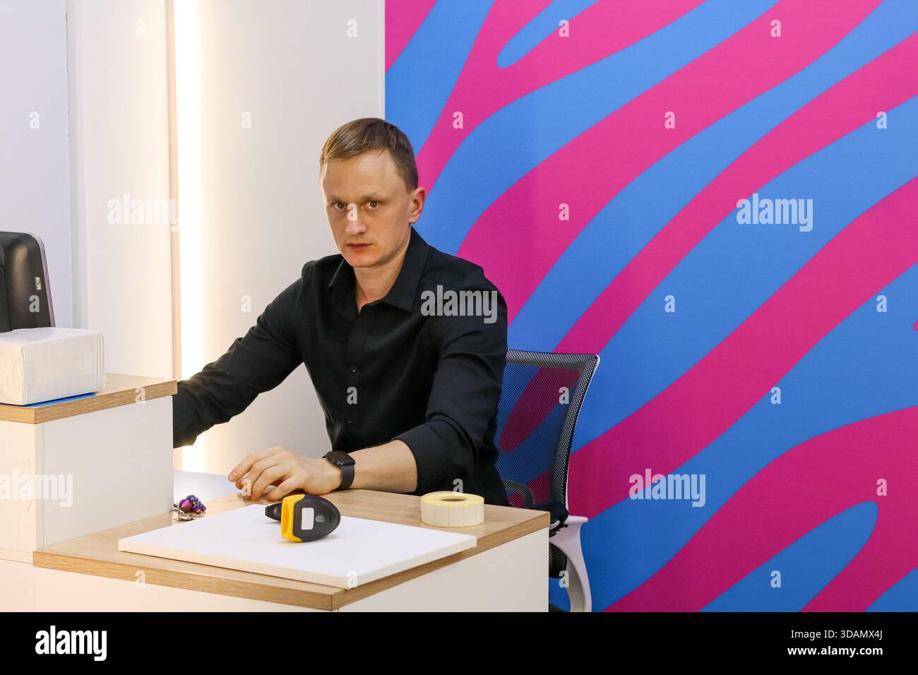 Les bras de l'employé reposent sur le bureau avec le lecteur à l'avant sur le mur rayé Banque D'Images