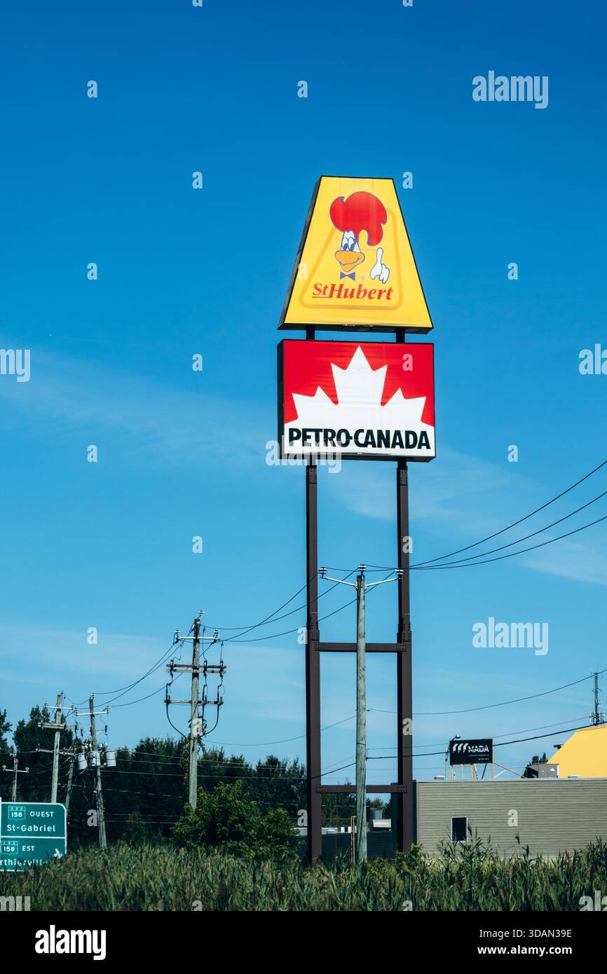 Trois Rivières, Canada - 15 août 2025 : panneau routier avec logo St Hubert au-dessus du logo Petro Canada sur fond bleu ciel Banque D'Images