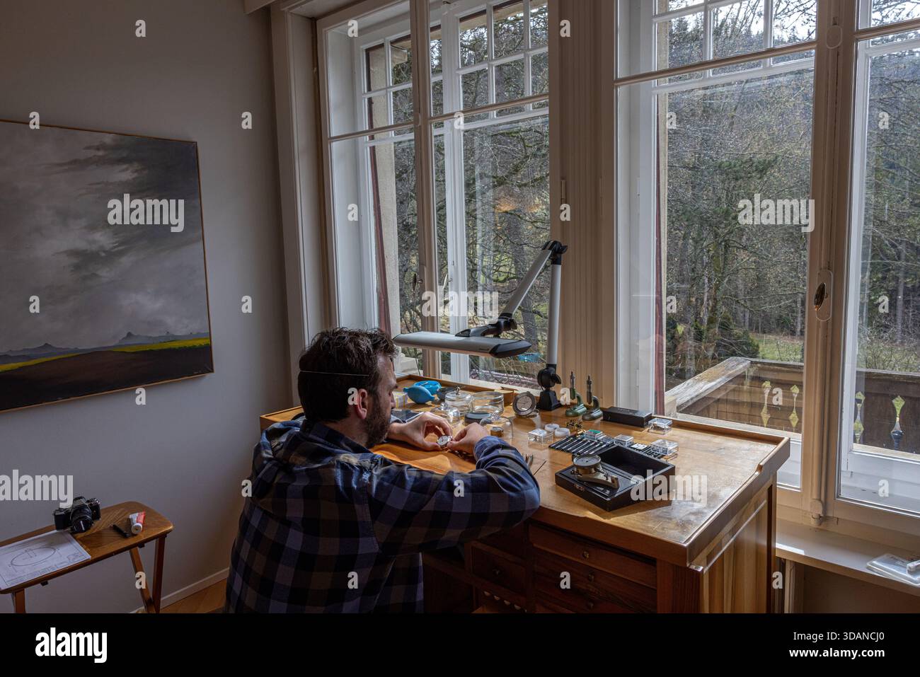 L'horloger indépendant Raul Pagès travaille sur une montre sur mesure dans son studio calme et ensoleillé aux Brenets, un village isolé dans les montagnes du Jura suisse Banque D'Images