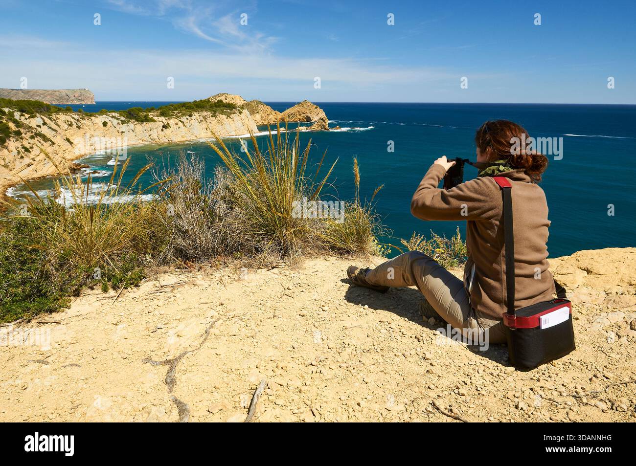 Photographe femme photographiant la plage de Portitxol et le cap Cap Prim depuis le point de vue du Mirador del Portichol (Jávea, Marina Alta, Alicante, Espagne) Banque D'Images