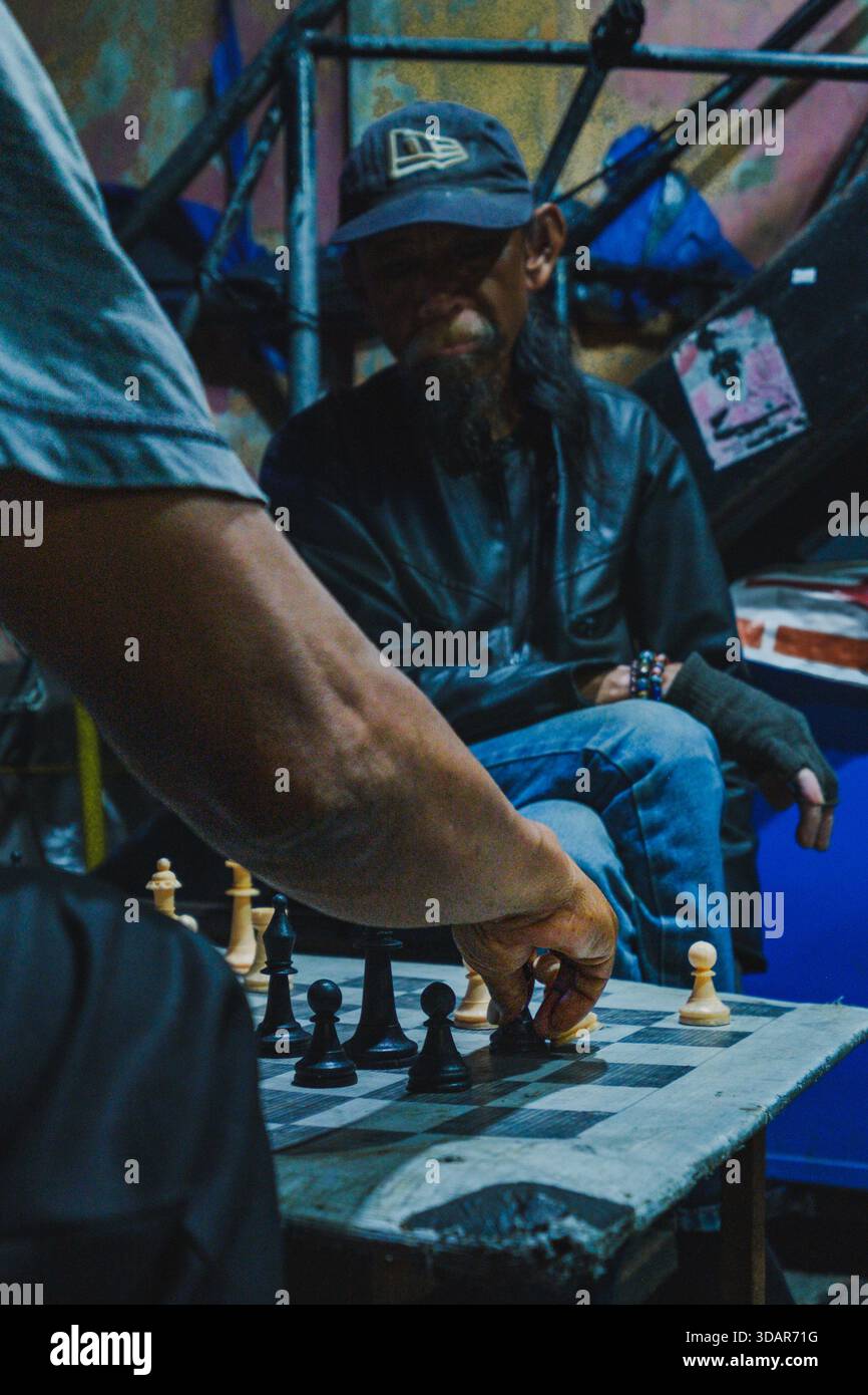 Balikpapan, Indonésie - 1er novembre 2025. Gros plan, photo sur l'épaule capturant la main d'un adversaire en train de déplacer une pièce lors d'un jeu d'échecs intensif Banque D'Images