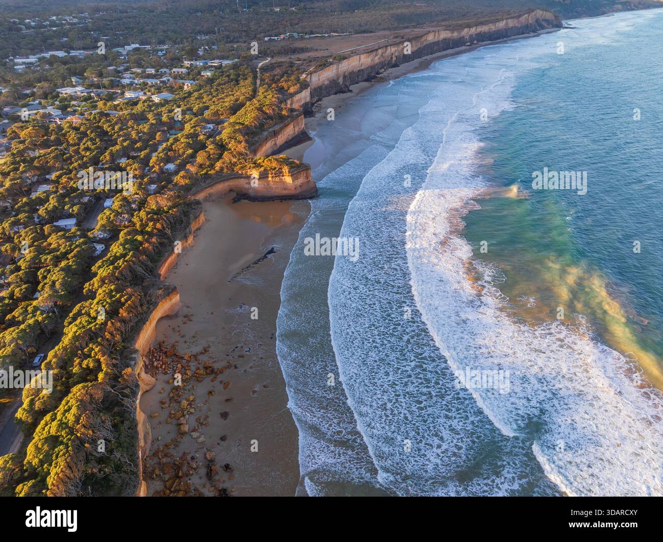 Vue aérienne des vagues se brisant le long d'une plage de sable sous une côte érodée à Anglesea sur la Great Ocean Road à Victoria, Australie. Banque D'Images