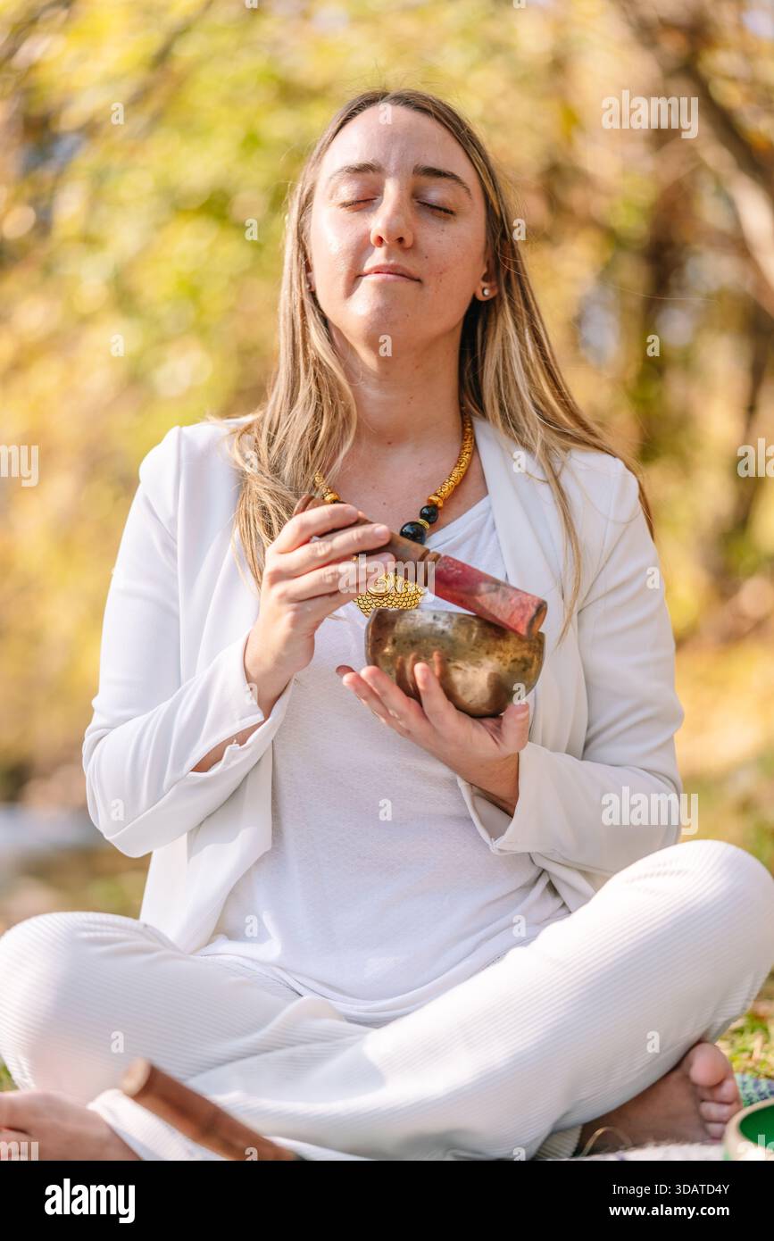 Femme méditant avec bol chantant dans la nature Banque D'Images