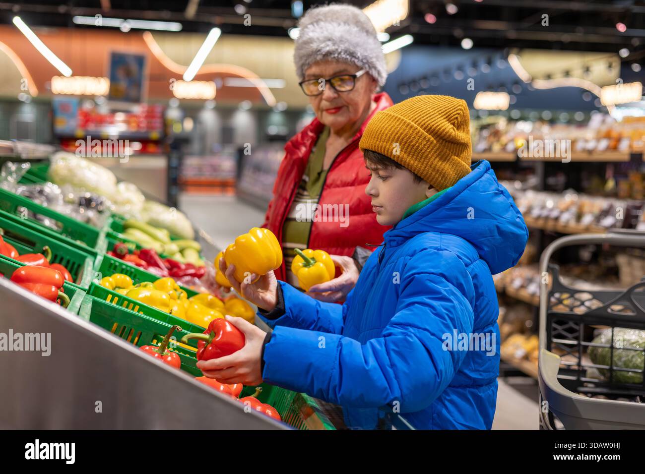 Grand-mère et petit-fils choisissant des légumes frais ensemble à la section des produits du supermarché. habitudes alimentaires saines, coopération intergénérationnelle, Banque D'Images