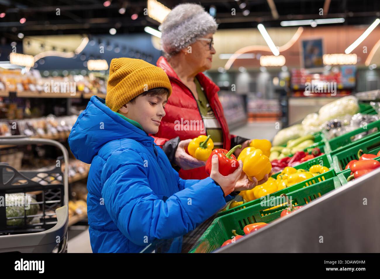 Grand-mère et petit-fils choisissant des légumes frais ensemble à la section des produits du supermarché. habitudes alimentaires saines, coopération intergénérationnelle, Banque D'Images