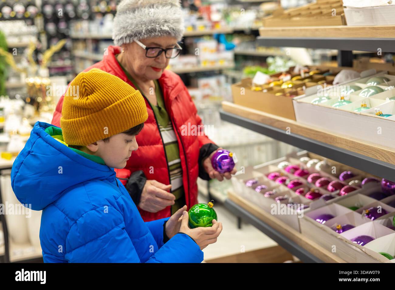 Garçon et femme âgée choisissant l'ornement d'arbre de Noël. Pendant le magasinage des Fêtes – la préparation des liens intergénérationnels et des traditions des Fêtes en famille Banque D'Images