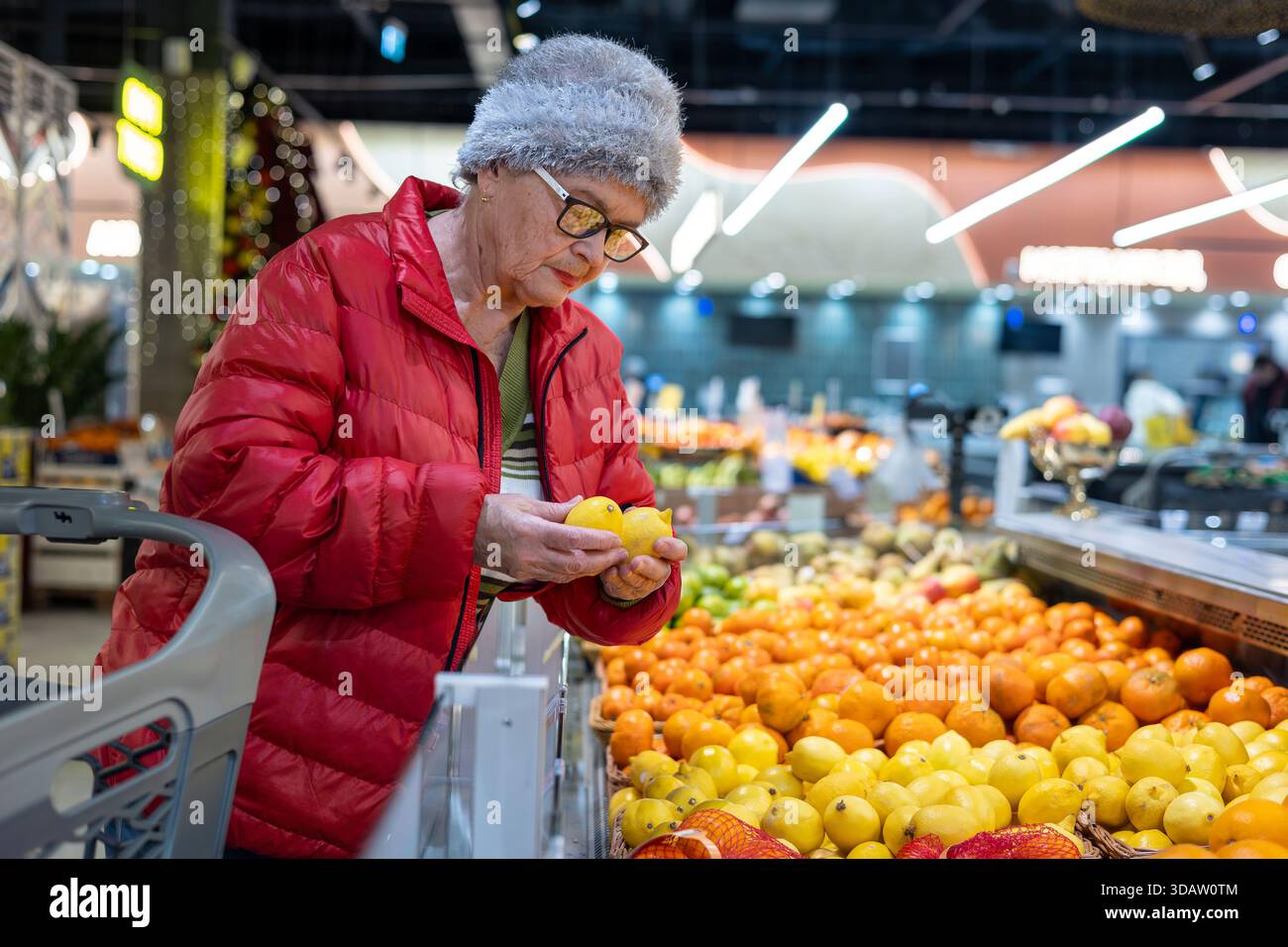 Femme âgée choisissant des citrons frais à la section des produits du supermarché – mode de vie senior actif, alimentation saine et shopping indépendant Banque D'Images