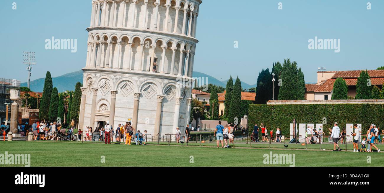 Pise, Italie - 26 juin 2025 : les niveaux inférieurs de la tour penchée dominent le cadre tandis que les visiteurs circulent le long des chemins clôturés, formant lin Banque D'Images
