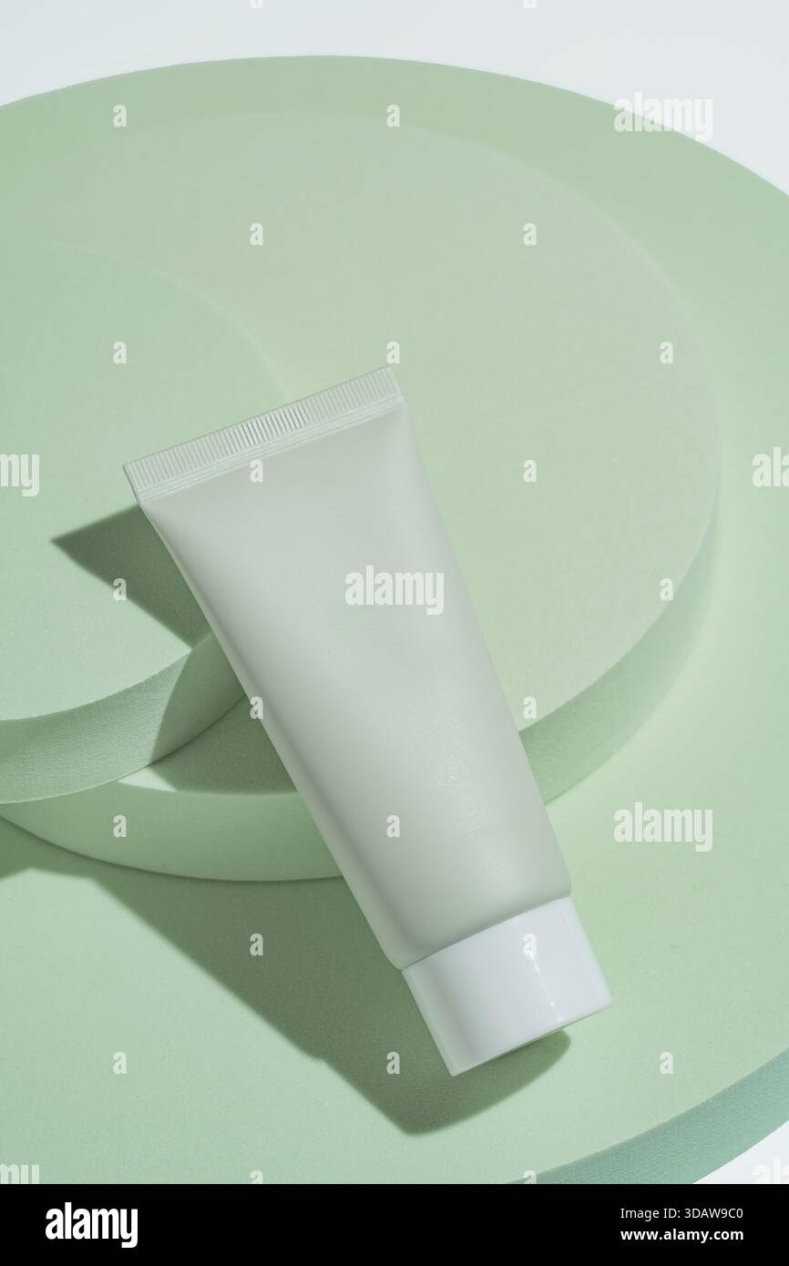 De dessus, un tube cosmétique vert élégant est élégamment positionné sur des podiums circulaires verts doux. L'arrangement minimaliste met en évidence le SO du produit Banque D'Images