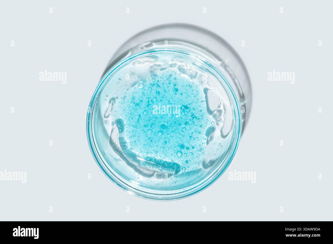 Vue de dessus d'une texture gel bleu éclatante à l'intérieur de la verrerie de laboratoire transparente. Les bulles claires et la surface lisse du gel contrastent avec Banque D'Images